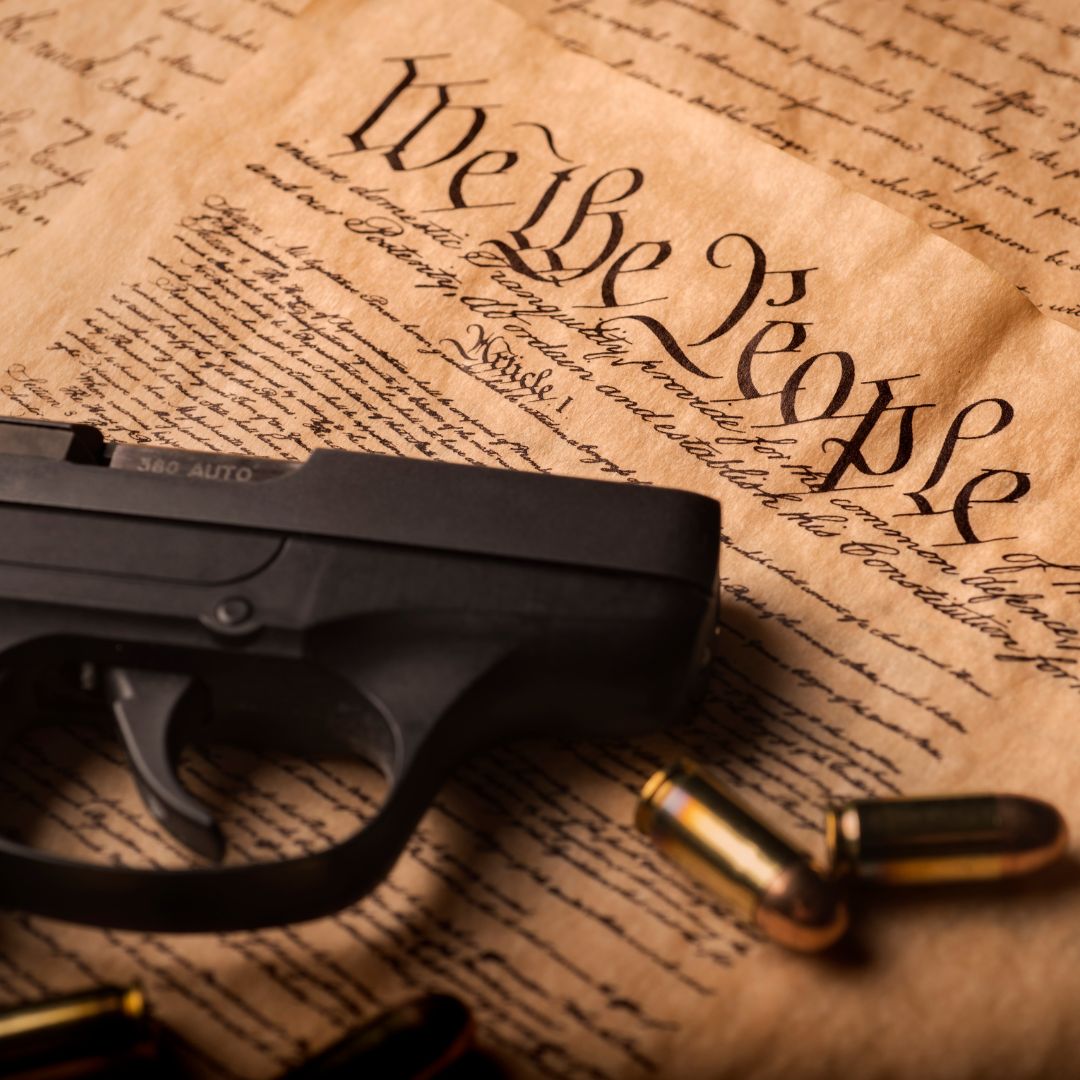 a gun laying on top of a copy of the constitution