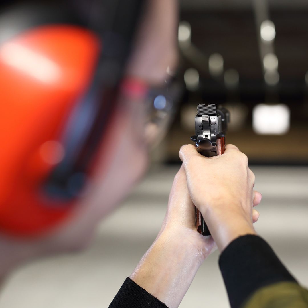a person shooting a gun at a gun range